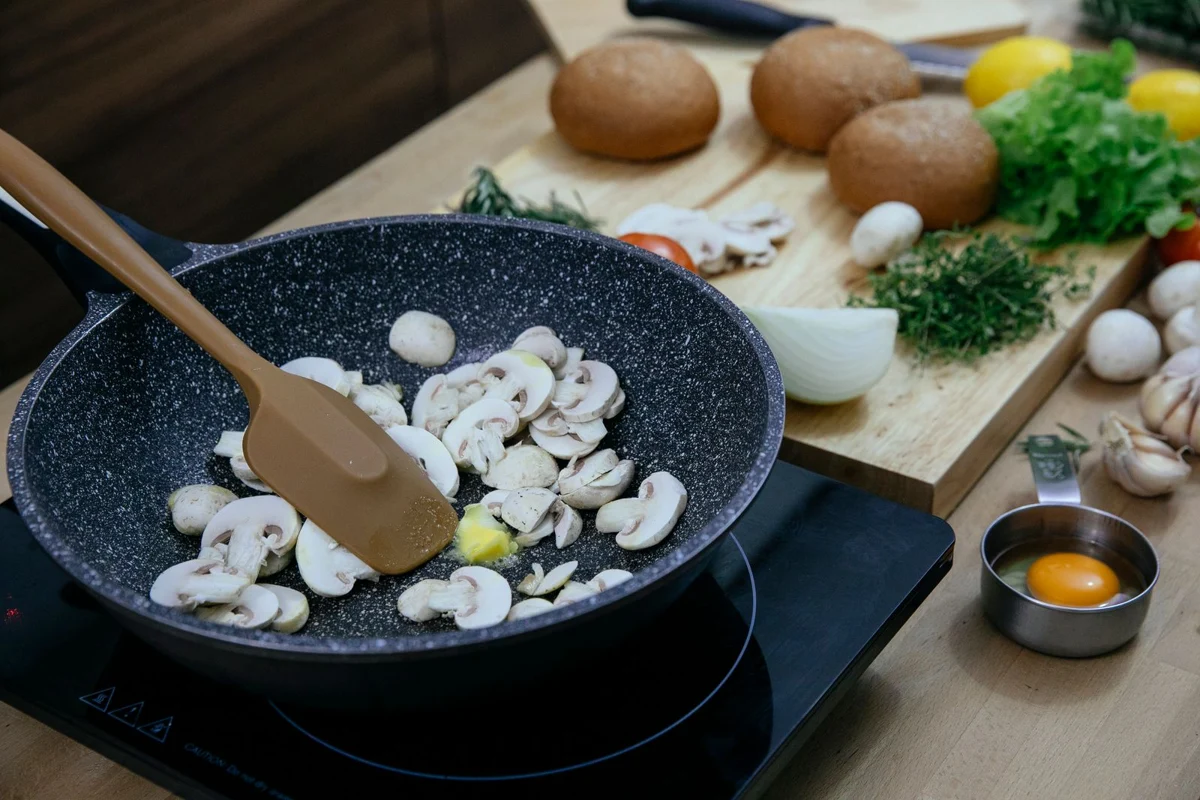 Mushrooms cooking in a pan with a silicone spatula