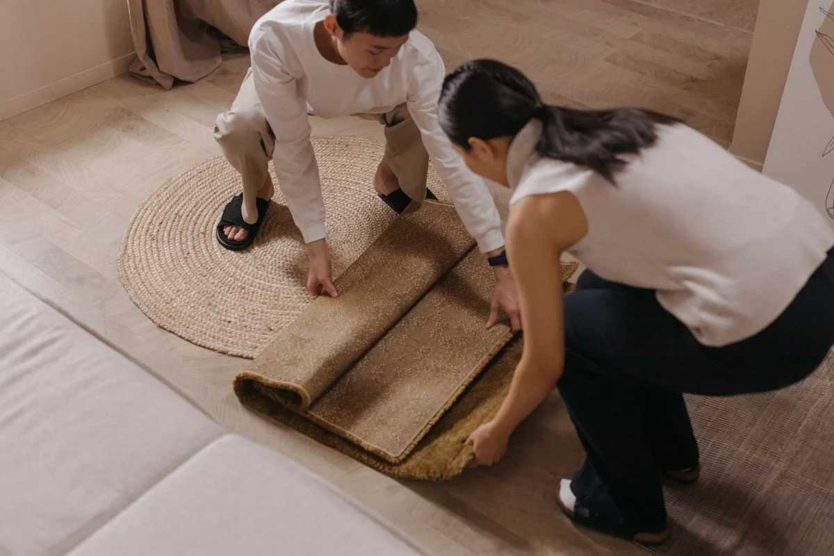 A rug being laid out on a living room floor