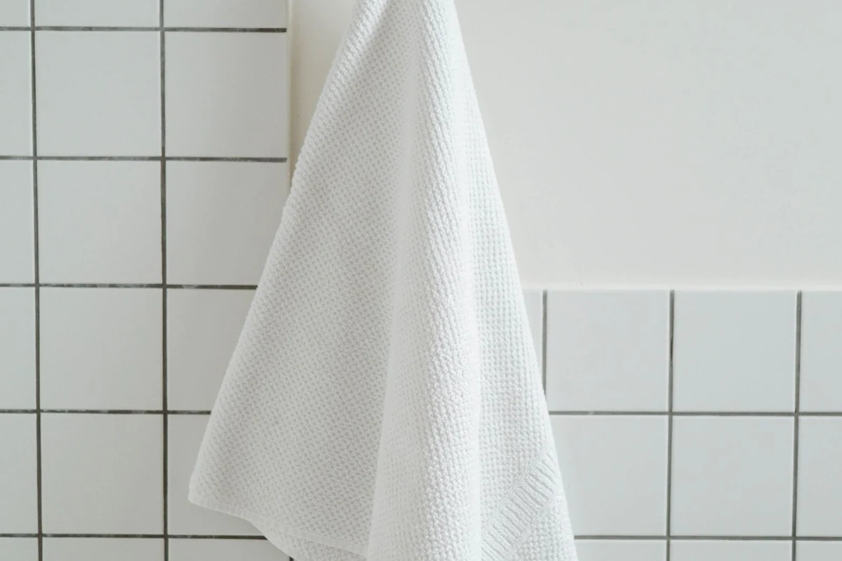 A white towel hanging in a tiled bathroom