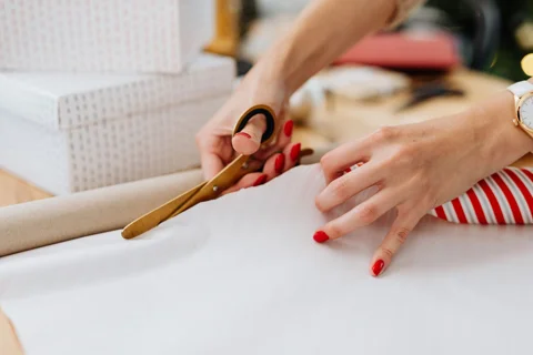 Hands cutting wrapping paper for a gift