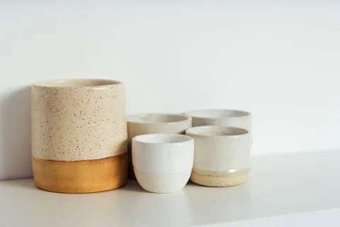 A group of ceramic cups on a kitchen shelf