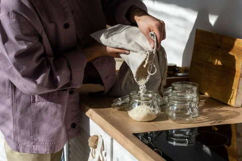 Rice poured from a cloth bag into a glass jar