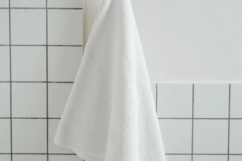 A white towel hanging in a tiled bathroom